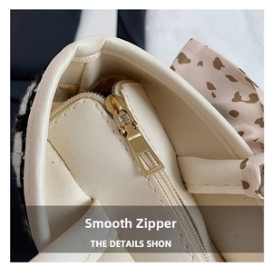 Detailed macro view of gold metal zipper and leopard print scarf on beige tote bag