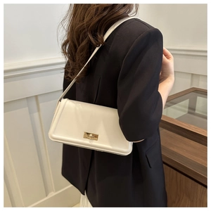Detail view of white faux leather crossbody bag featuring a golden rotary buckle closure