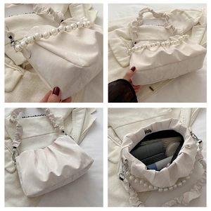 Detail view of beige ruched bag featuring large pearl handle and soft pleated PU leather