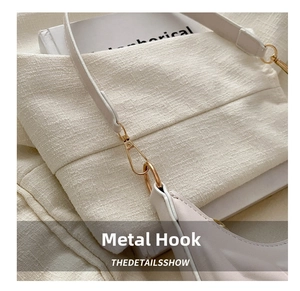 Detailed close-up of premium gold hardware hook on a beige crescent shoulder bag