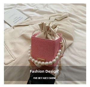 Detailed shot of pink woven bucket bag with large pearl handle and gold chain strap