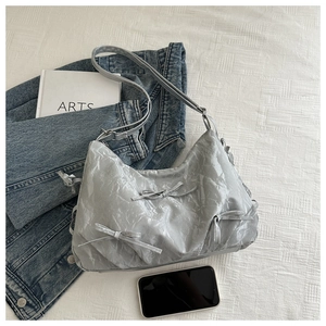 Silver-grey bow bag with metallic texture shown next to a smartphone for size reference
