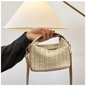 Detailed view of beige straw woven bag with leather handles and metallic zipper closure