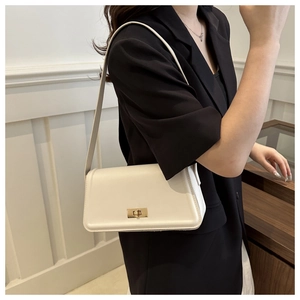 Close-up of cream crossbody bag featuring a gold twist lock and sleek faux leather finish