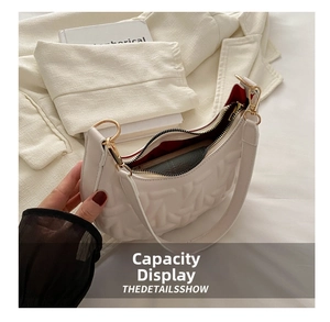 Detailed view of white crescent bag with woven texture, red lining and gold hardware