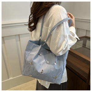 Detailed view of light blue tote bag with elegant silver butterfly metal accents