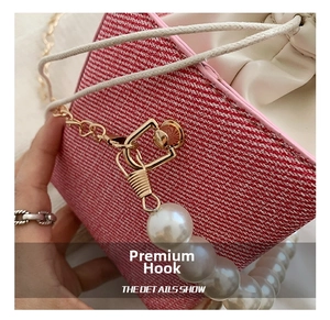 Detail of red tweed bucket bag with large pearl strap and golden metal hook closure