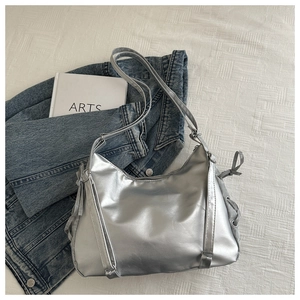 Detail of silver matte shoulder bag featuring side bow ties and smooth metallic texture