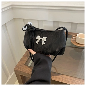 Detail of black pleated shoulder bag with silver butterfly charm and beaded strap accents