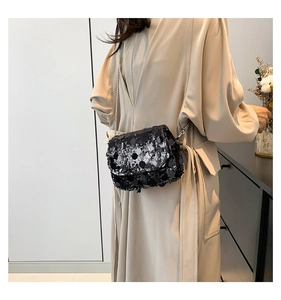Detail of a chic crossbody bag with black sequins and a silver chain strap on model