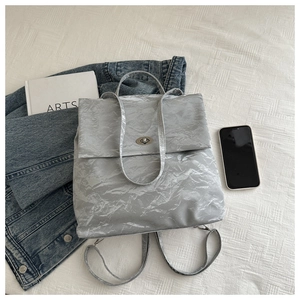 Macro detail of metallic silver pleated fabric and metal clasp on luxury shoulder bag