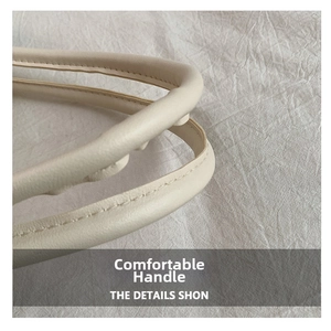 Close-up of beige tote bag handle showing high-quality stitching and textured leather