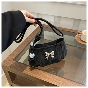 Detail of black pleated shoulder bag featuring a silver bow and decorative frosted beads