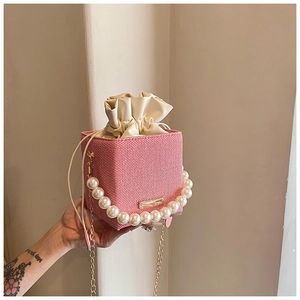 Détail du sac seau tissé rouge et blanc avec poignée en perles et chaîne dorée