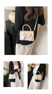 Detail of creamy white bow handbag featuring glossy finish and detachable shoulder strap