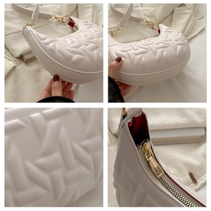 Close-up of geometric embossed leather and red lining on white crescent handbag