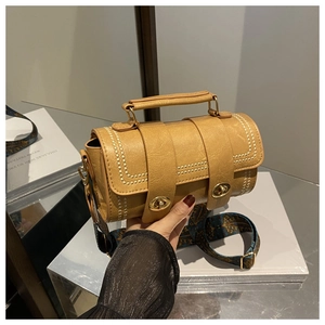 Detail of camel cylinder bag with gold hardware and ethnic style wide shoulder strap