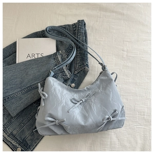 Flat lay of light blue bow handbag on denim jacket with artistic textured surface
