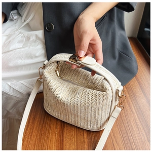 Detailed view of woven texture and premium gold hardware on a chic straw handbag
