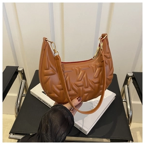 Detail view of brown half-moon bag featuring unique geometric quilted texture and gold hardware