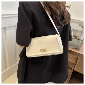 Detailed close-up of white leather crossbody bag with gold rotating lock and chain strap