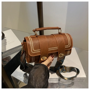 Detail of vintage brown cylinder bag with white stitching and patterned wide strap
