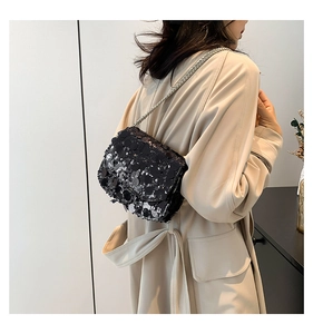 Detail view of the black sequined shoulder bag with a silver metal chain strap