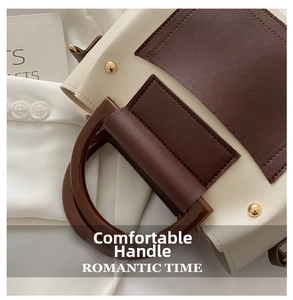 Close-up of contrast color Boston bag with round handle and gold rivet details