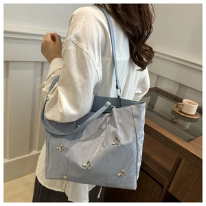 Detail of light blue bucket bag with silver butterfly charms and delicate pleat texture