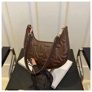 Close-up of brown embossed crescent bag with gold zipper and vibrant red interior lining