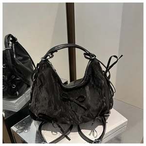 Detail of the black pleated crescent bag with bow decoration and silver metal zipper