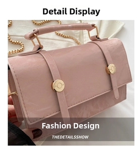 Detailed shot of pink textured leather crossbody bag with gold chain strap and dual buckles