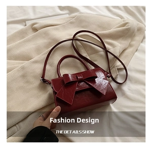 Detail of burgundy patent leather handbag with bow and elegant crossbody strap