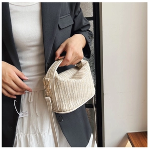 Close-up of straw woven bag with white leather straps and gold metal hardware