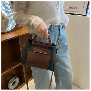 Detail of retro color-block handbag with wooden handle and adjustable leather strap