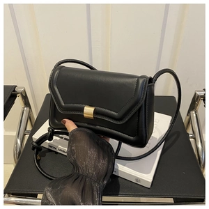 Detail of a black rectangular saddle bag with a gold metal clasp on a vintage book