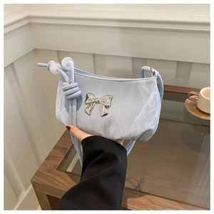 Detail of light blue marble textured bag with silver metal bow and knotted rope strap