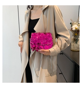Detail of rose red sequin crossbody bag with silver chain strap on fashion model