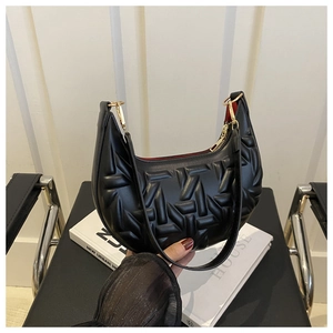 Detail of black crescent bag featuring 3D geometric quilting and gold hardware accents