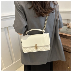 Detailansicht einer cremeweißen Ledertasche mit Rautensteppung und goldener Kette