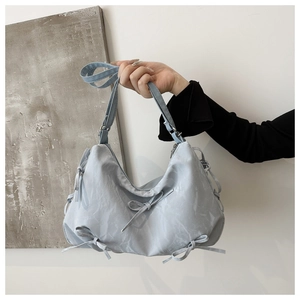 Detail of light blue bow handbag featuring ruffled texture and silver metal zipper