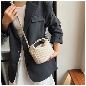 Detail of cream woven bucket bag showing textured V-pattern straw and crossbody strap
