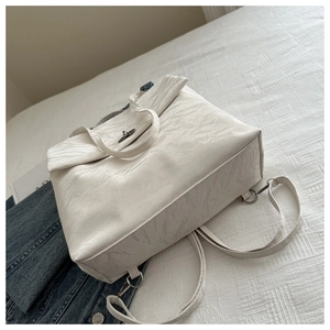 Close-up of cream textured faux leather bag with silver metal twist lock closure