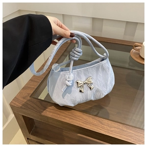 Light blue pleated shoulder bag with silver bow and beaded handle detail in life scene