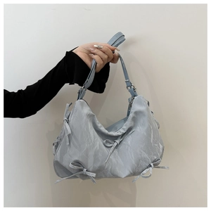 Detail of light blue crossbody bag with ribbon bows and pleated marble texture fabric