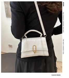Detail of white crocodile pattern handbag with gold clasp and crossbody strap