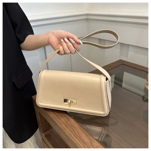 Close-up of beige leather tote bag featuring a gold rectangular metal swivel lock clasp