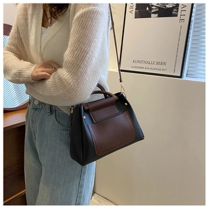 Detail of a two-tone crossbody bag in black and brown faux leather worn by a model