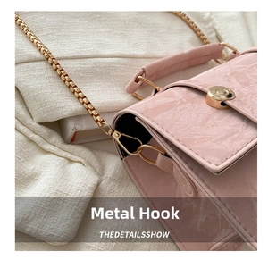 Detail of golden metal chain and hook on a pink marble textured crossbody bag