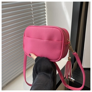 Dettaglio della borsa a tracolla rosa con trama in pelle e nappa decorativa